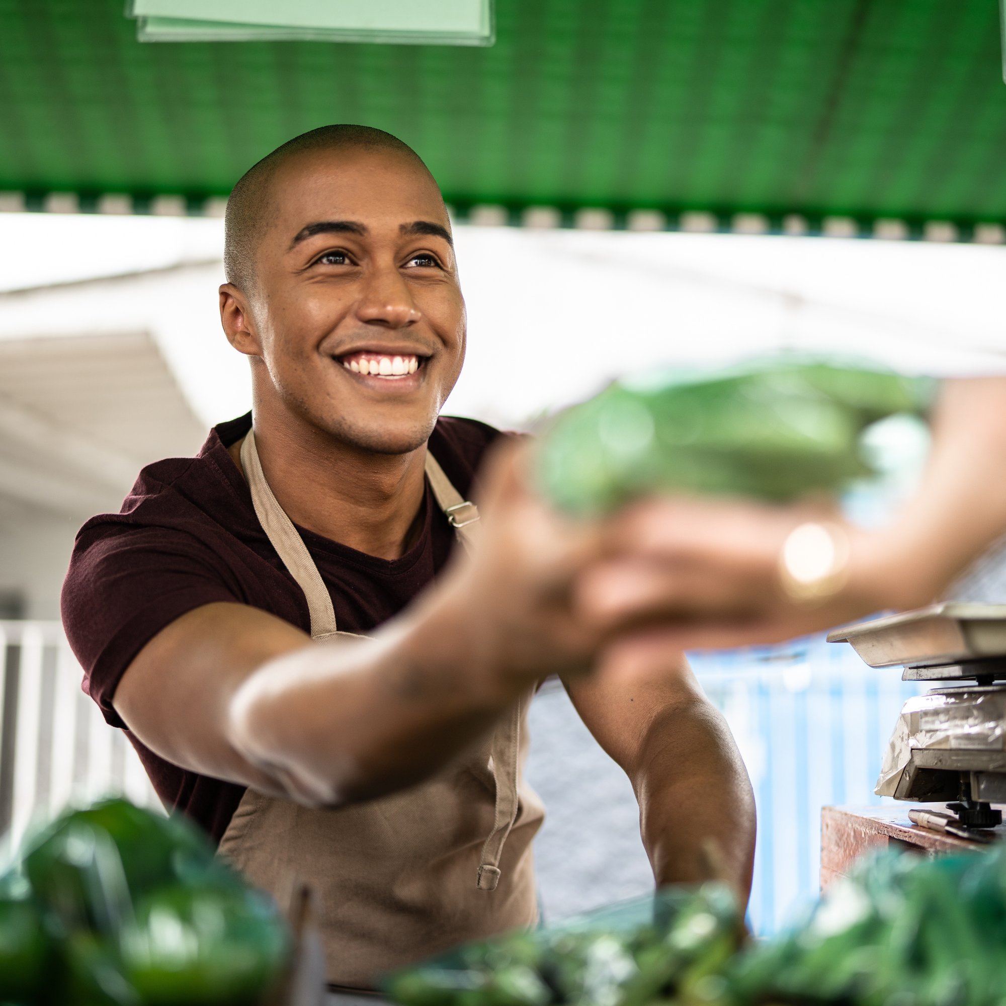 young male fruit and veg shop stall worker_iStock-1369521403