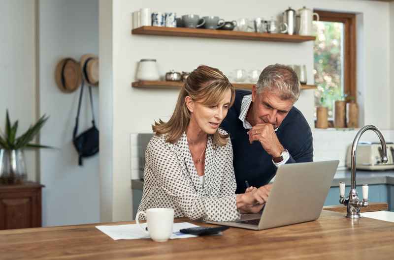 A senior couple planning their finance and paying bills while using a laptop at home_iStock-1399376478-1