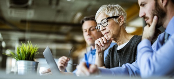 Senior businesswoman and her colleagues using laptop in the office_iStock-1188356266-1