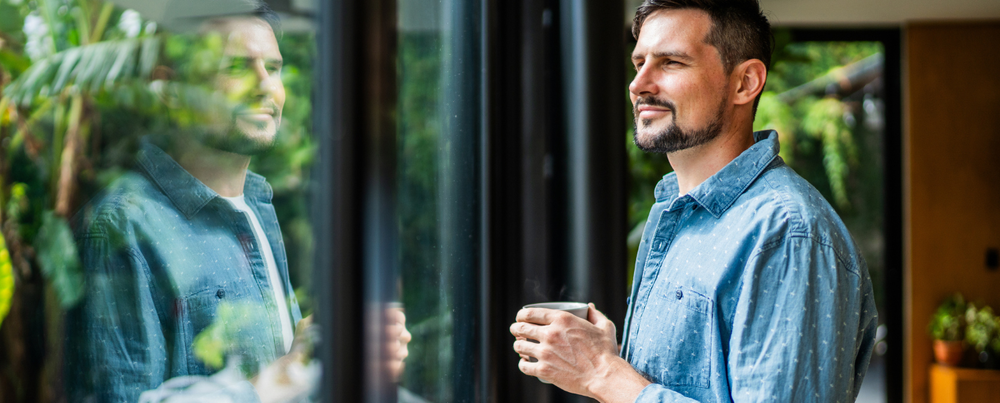 Guy drinking coffee looking outside through a window