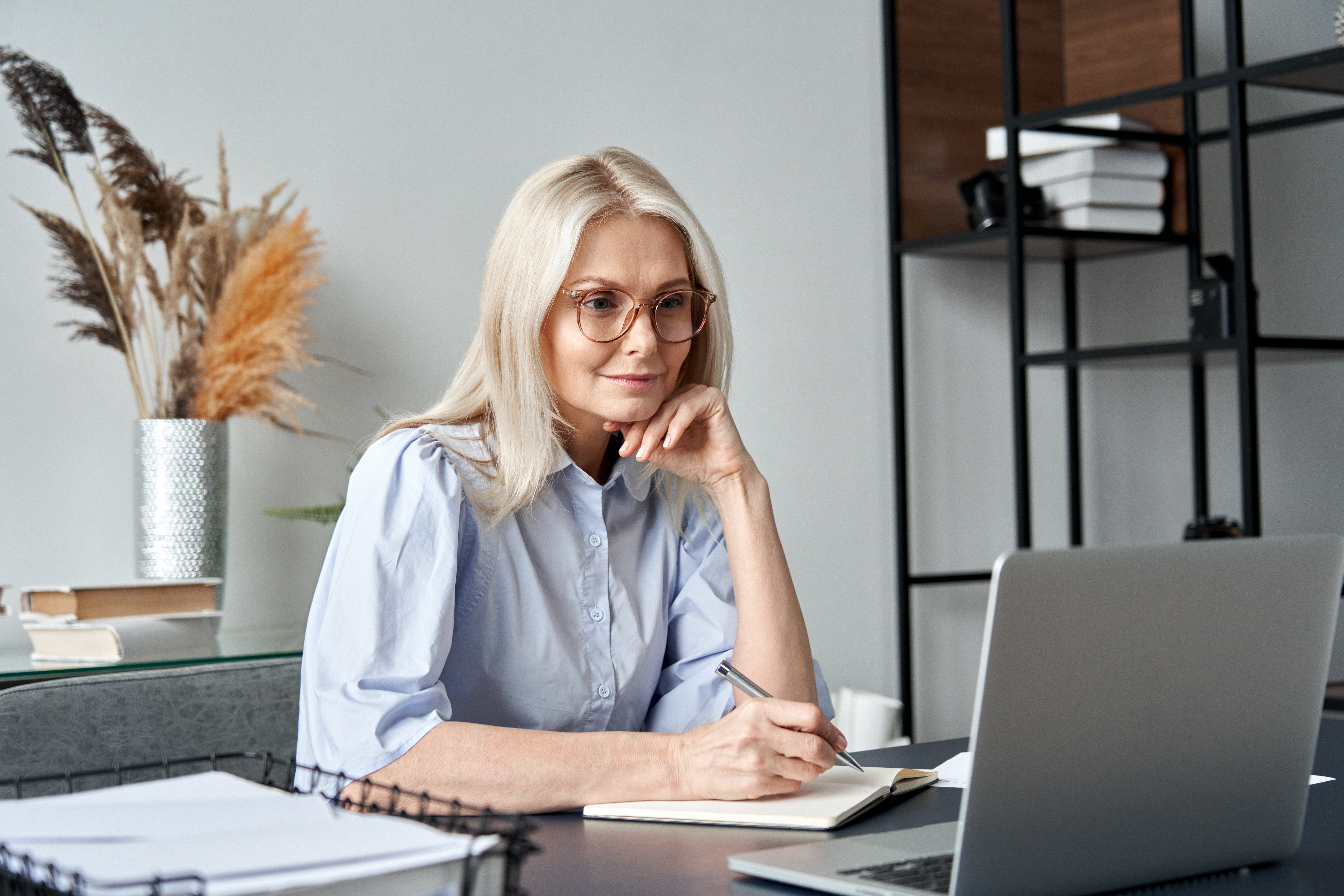 lady watching a webinar taking notes at home_iStock-1303367756
